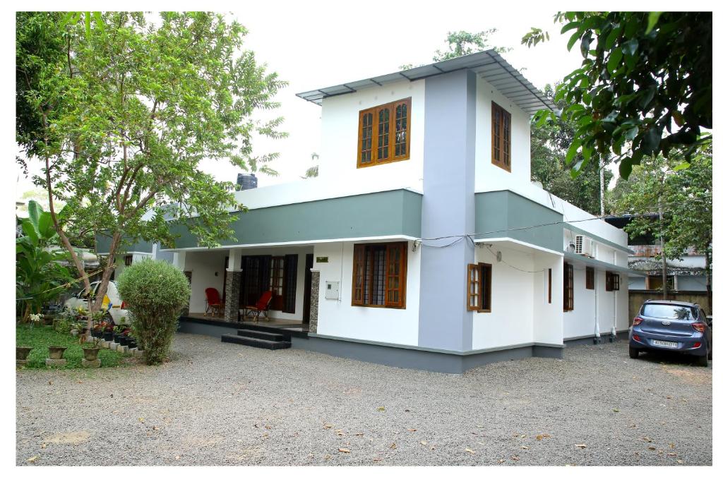 uma casa branca com um carro estacionado na garagem em Snehatheeram Homestay em Alappuzha