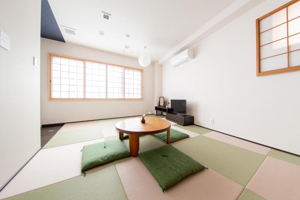 Zimmer mit einem Tisch und grünen Kissen auf dem Boden in der Unterkunft Yado Hachiemon in Osaka