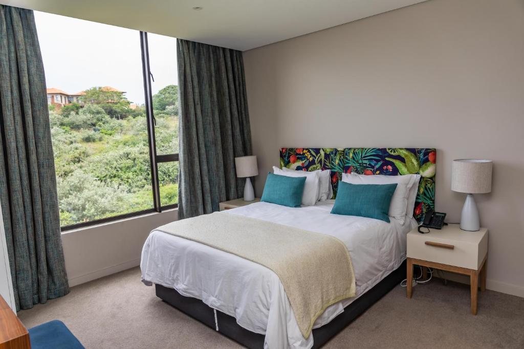 a bedroom with a bed and a large window at Zimbali Suite 205 in Ballito