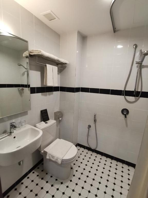 a bathroom with a toilet and a sink and a shower at Kimberley Hotel Georgetown in George Town