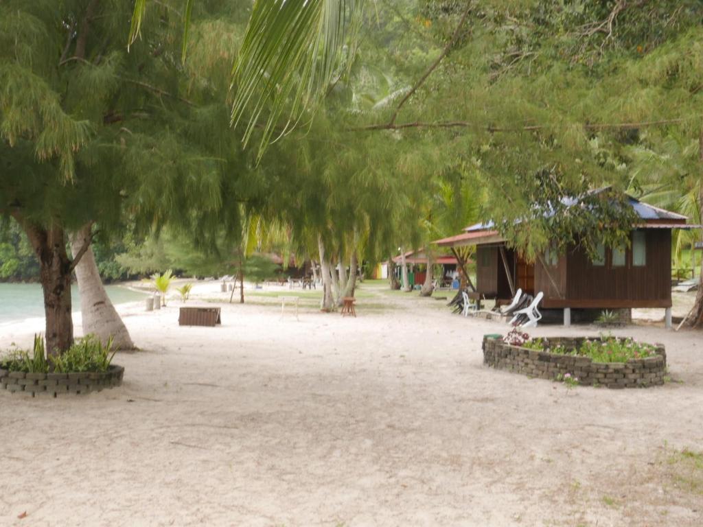 ein Park mit einem Gebäude, einem Baum und Bänken in der Unterkunft Beach Front Villa 1 pasir panjang in Kuah
