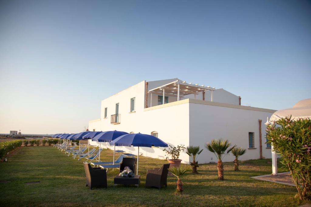 un groupe de chaises et de parasols devant un bâtiment dans l'établissement Relais Antiche Saline, à Torre Nubia