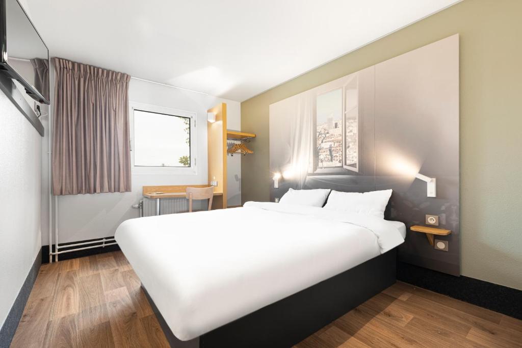 ein großes weißes Bett in einem Zimmer mit Fenster in der Unterkunft B&B HOTEL Lyon Centre Monplaisir in Lyon