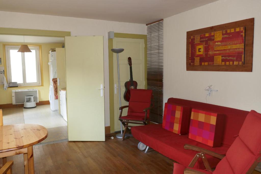 uma sala de estar com um sofá vermelho e uma mesa em Les Jonquilles em La Bresse