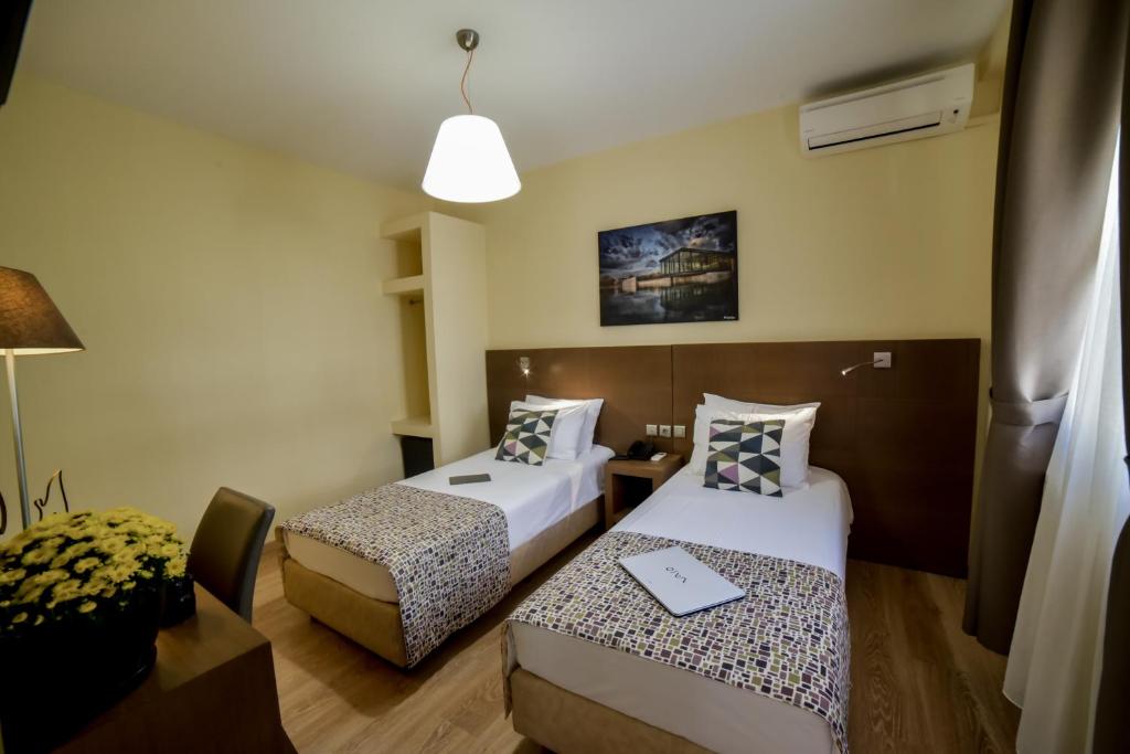 a hotel room with two beds and a desk at Orestias Kastorias in Thessaloniki