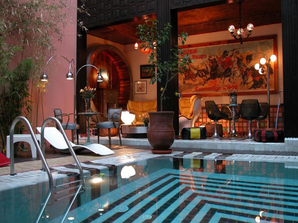 a large swimming pool with chairs and a table at Riad Malika in Marrakesh