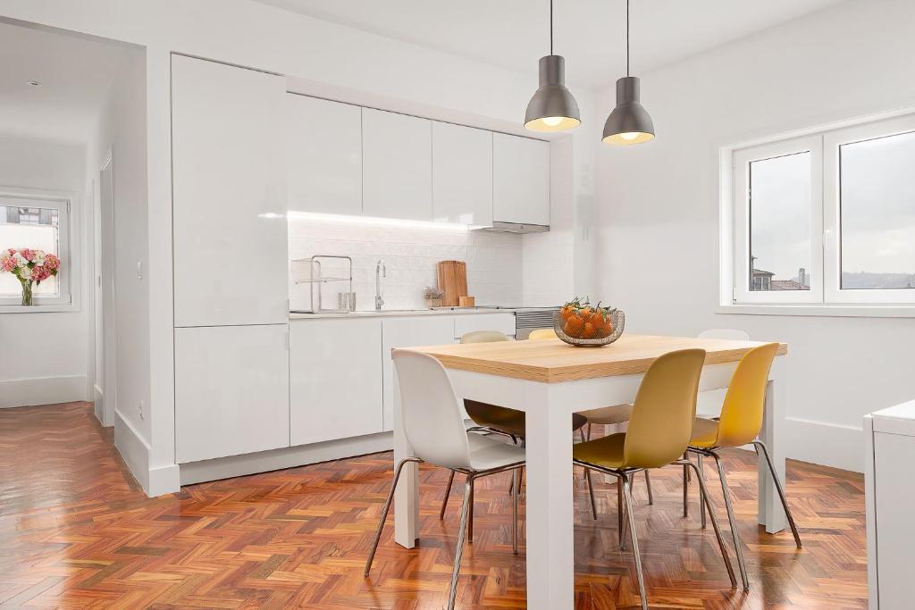 a white kitchen with a wooden table and chairs at Oporto Classic Pàtio in Porto