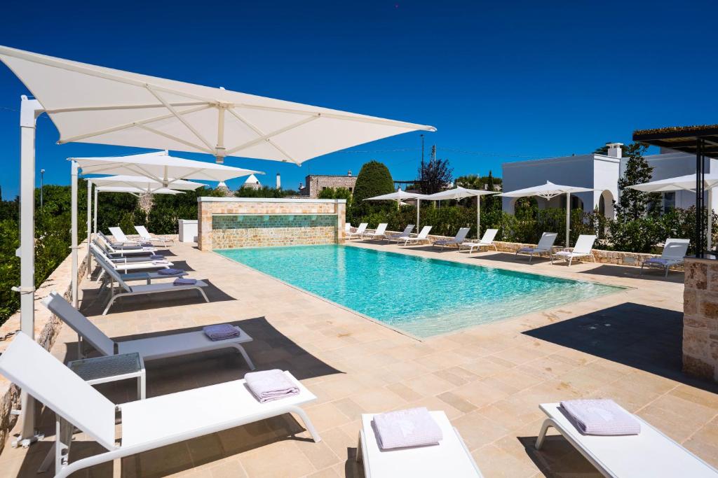 a swimming pool with lounge chairs and umbrellas at Borgo Cozzana in Monopoli