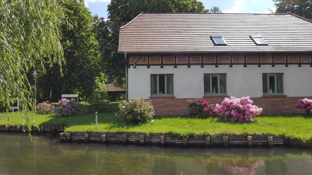 uma casa com flores em frente a um rio em "Spreehof" Apartmenthaus in Lehde em Lübbenau