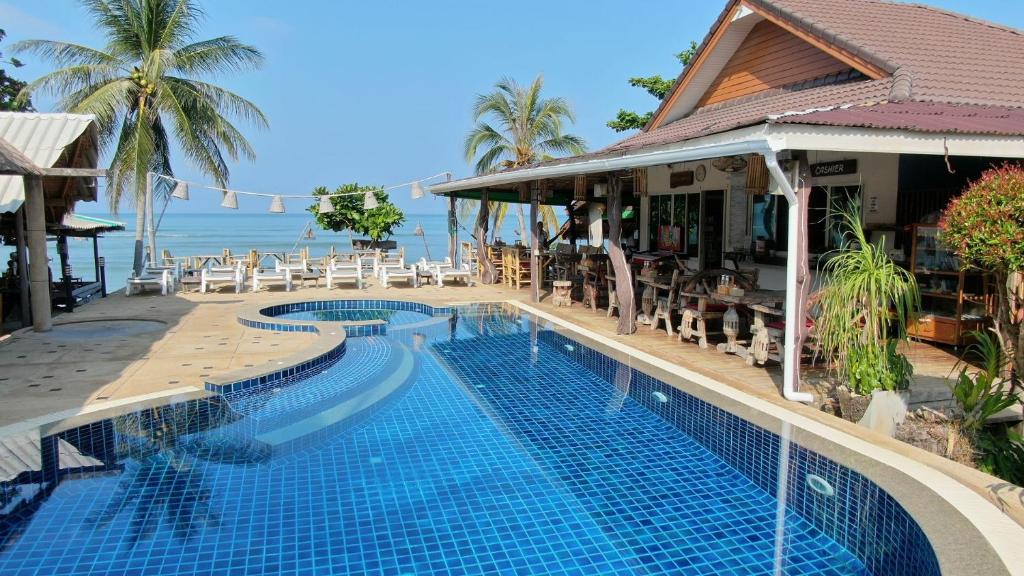 a swimming pool in front of a resort with the ocean at Lanta New Coconut Bungalow in Ko Lanta
