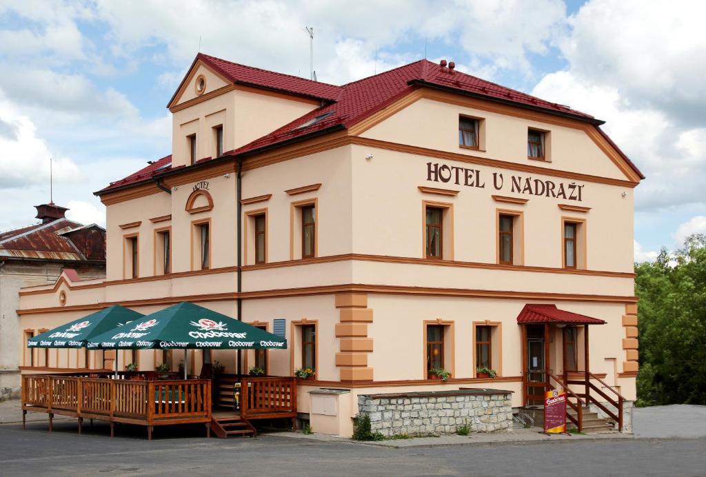 een gebouw met tafels en parasols ervoor bij Hotel U Nádraží in Tepla