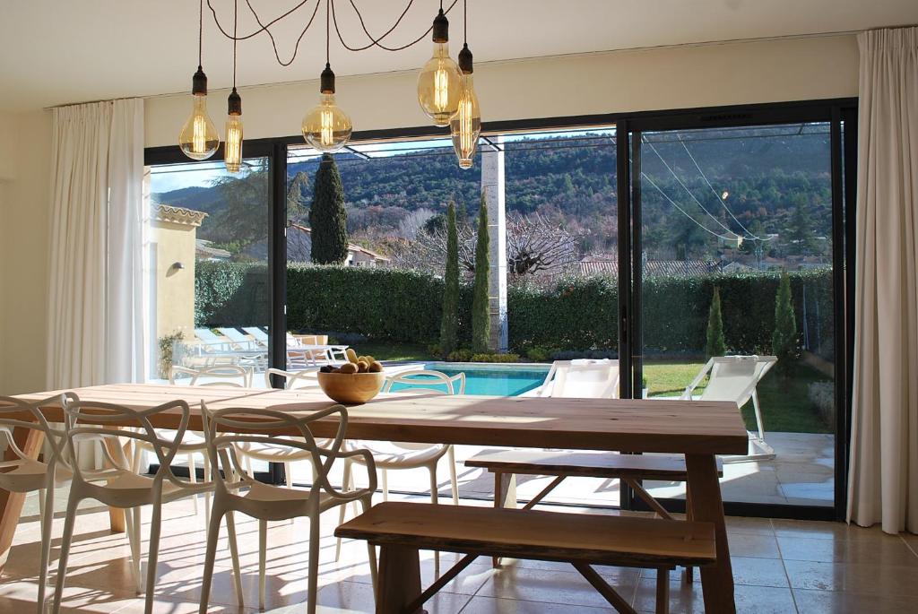 a dining room with a table and chairs and a pool at Villa Marièle in Malaucène