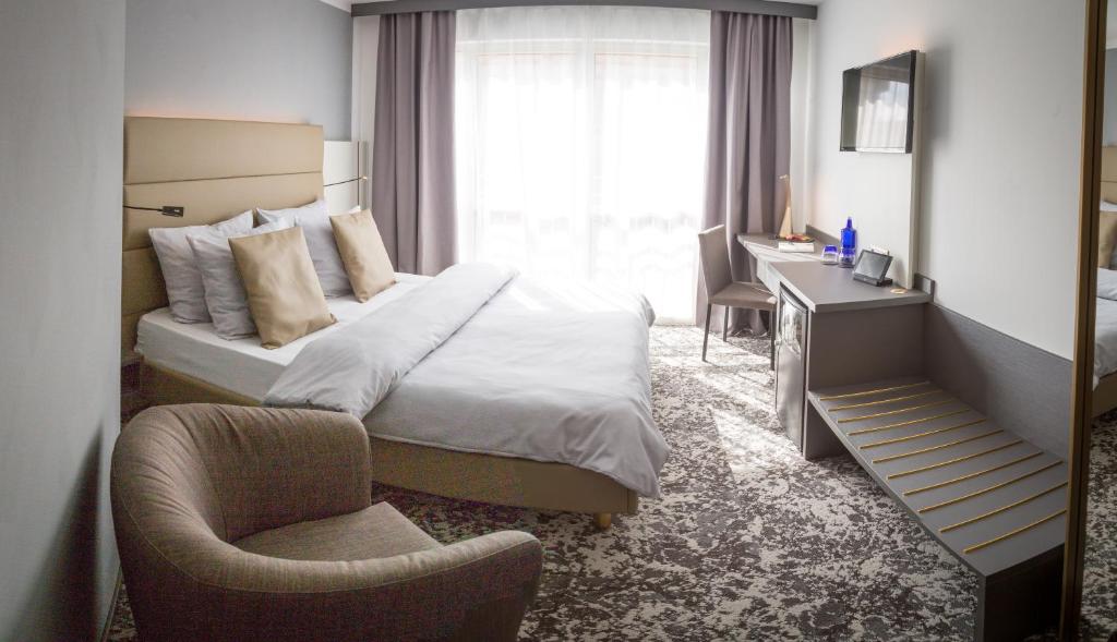 um quarto com uma cama, uma cadeira e uma secretária em Hotel Santo em Karlsruhe