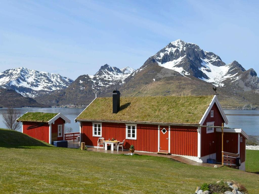 una casa roja con techo de hierba con montañas al fondo en Two-Bedroom Holiday home in Gravdal 2, en Gravdal