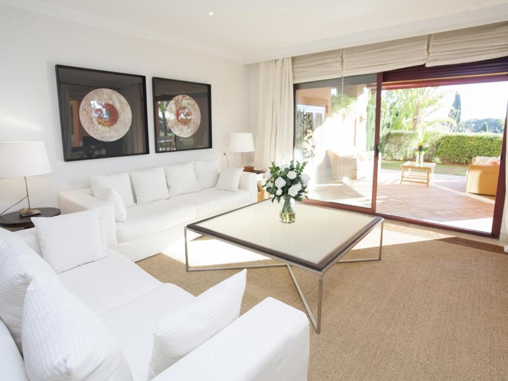 ein Wohnzimmer mit weißen Möbeln und einem Glastisch in der Unterkunft GRAN BAHIA de Marbella in Marbella