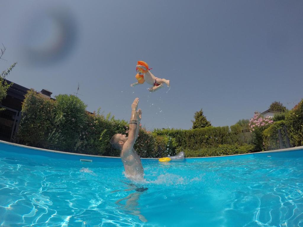 two people are in a swimming pool at Villino Vacanze "Il Porticciolo" in Manerba del Garda