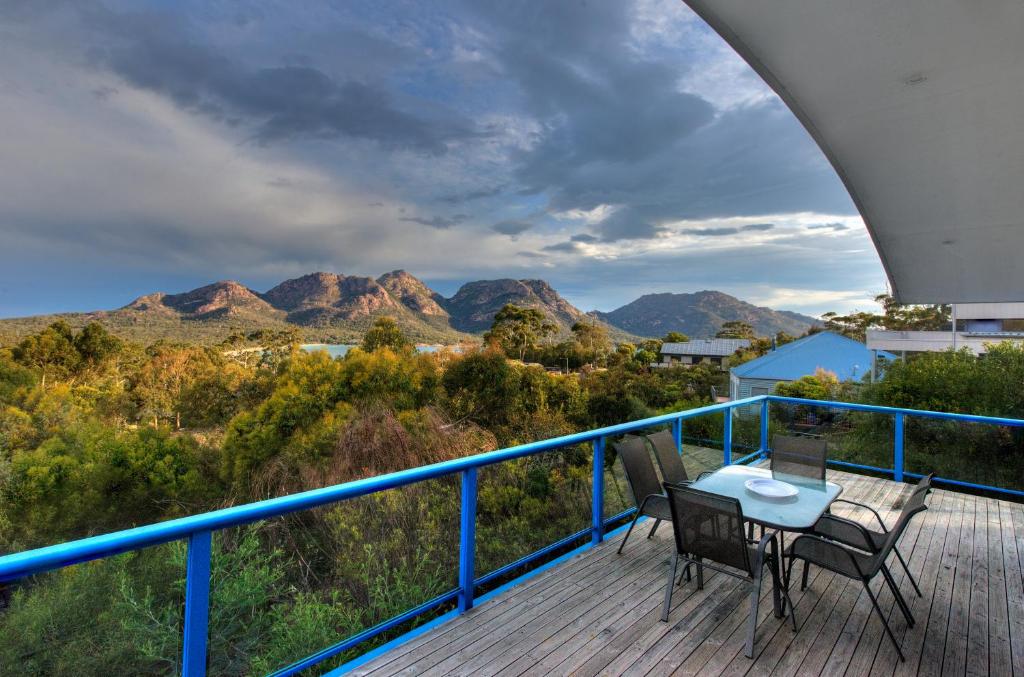 a deck with two chairs and a table with a view of mountains at Blue Gum Retreat in Coles Bay