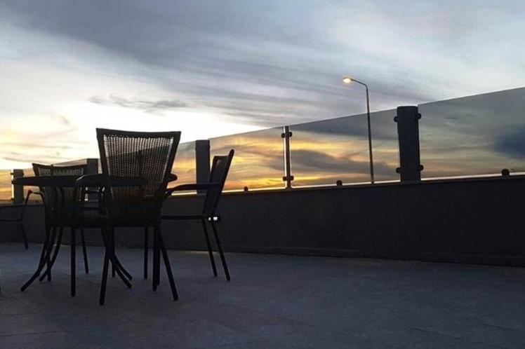 two chairs and a table on a balcony with the sunset at צימרים שירת הכוכבים in Mitzpe Ramon