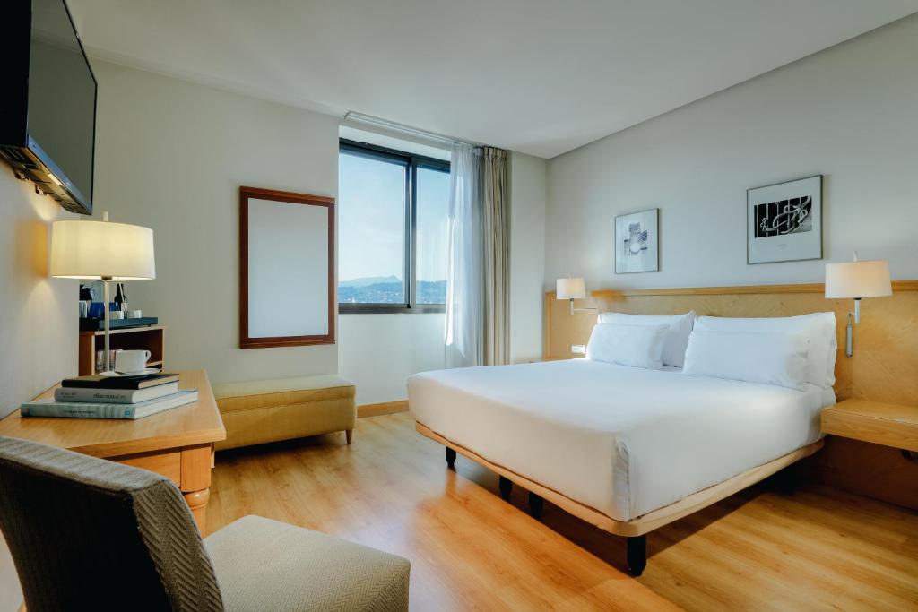 a hotel room with a bed, desk, and chair at Hesperia Vigo in Vigo