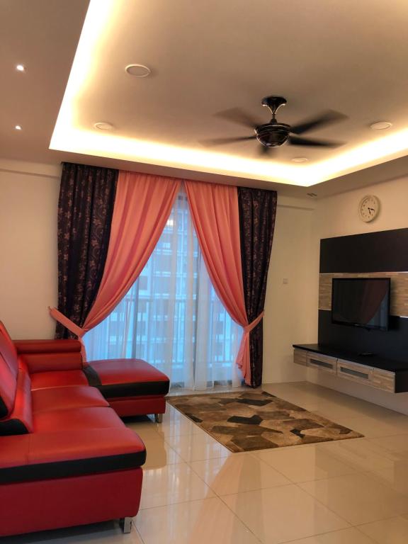 uma sala de estar com um sofá vermelho e uma televisão em KJ Homestay Casa Kayangan em Ipoh
