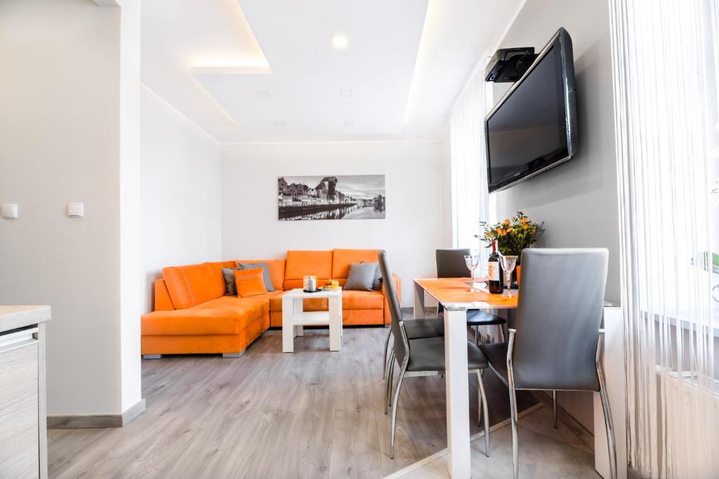 a living room with an orange couch and a table at Hamlet Old Town Apartment by TriApart in Gdańsk
