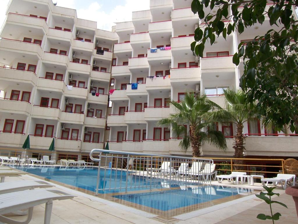 a hotel with a swimming pool in front of a building at Semiz Apart Hotel in Alanya