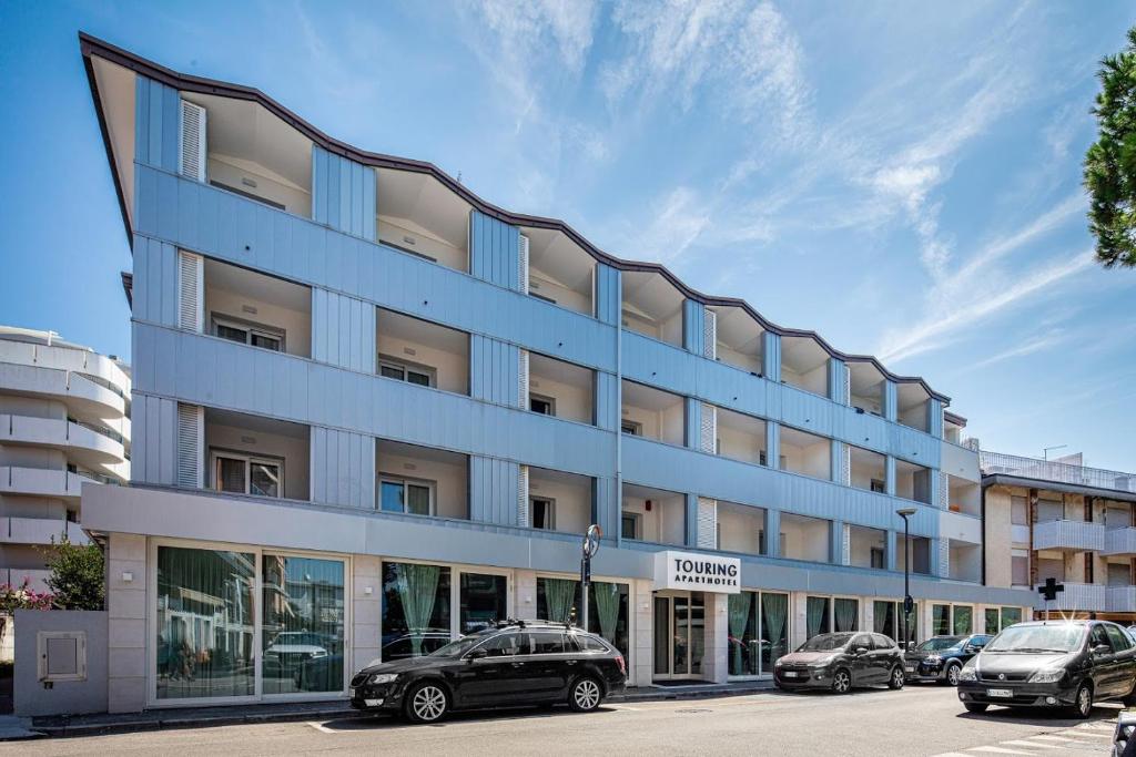 un edificio con coches estacionados frente a él en Aparthotel Touring, en Grado