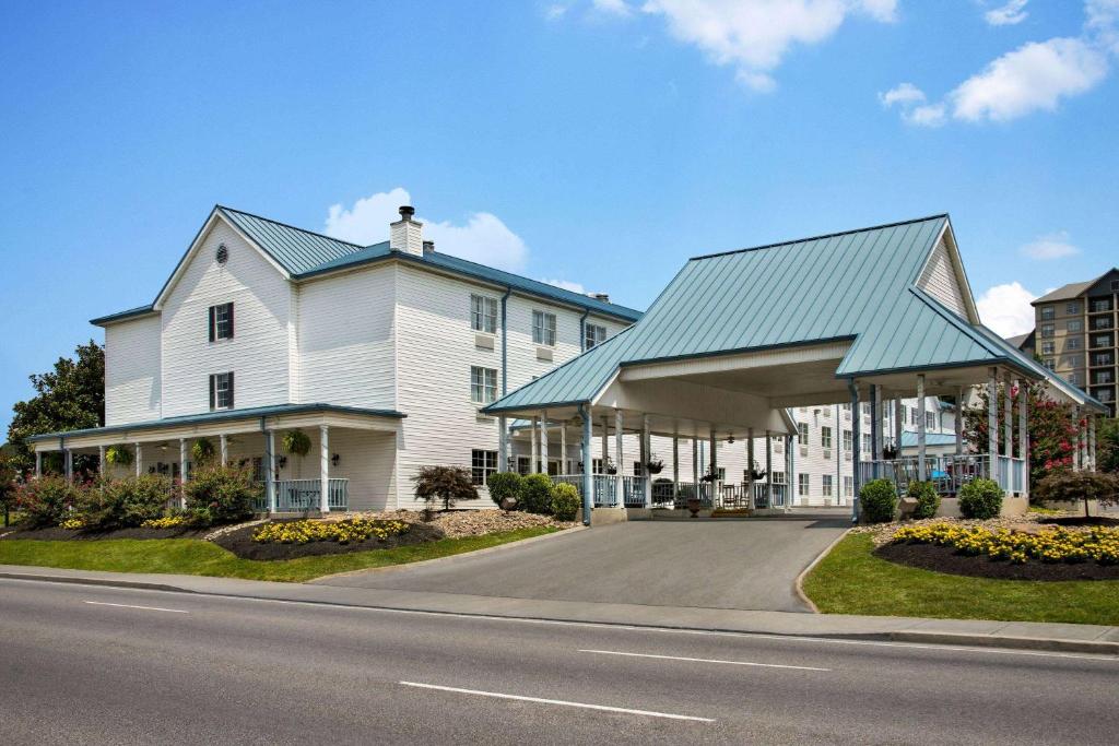 a white house with a blue roof on a street at Ramada by Wyndham Pigeon Forge North in Pigeon Forge