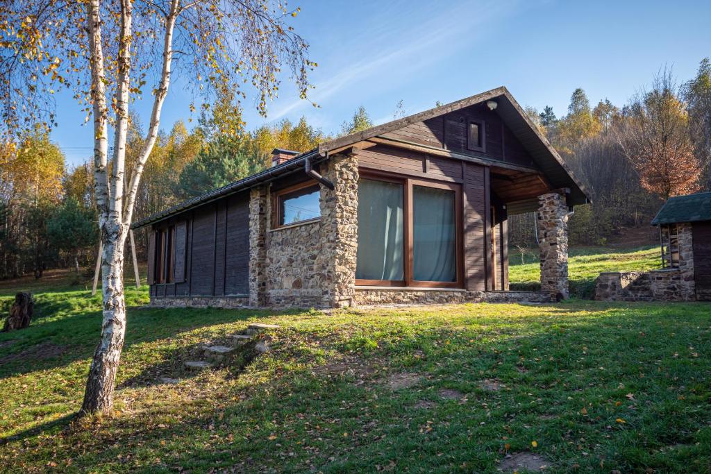 a stone house in the woods with a tree at Siedlisko Zagórze in Nowa Huta