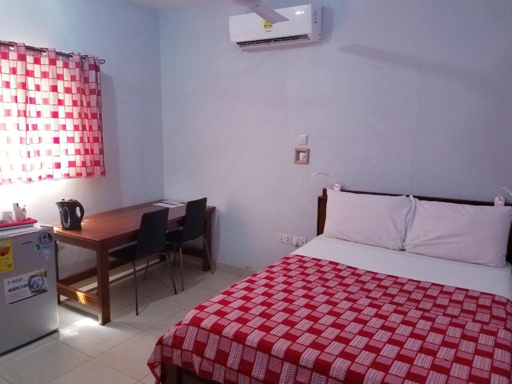 a bedroom with a bed and a desk and a table at Sharp Guesthouse in Accra
