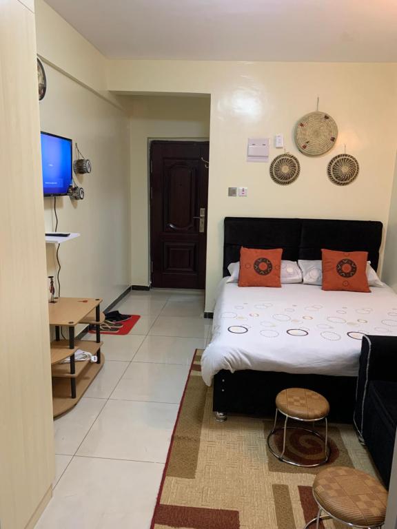 a bedroom with a bed with orange pillows and a tv at Ruthys Apartment in Nairobi