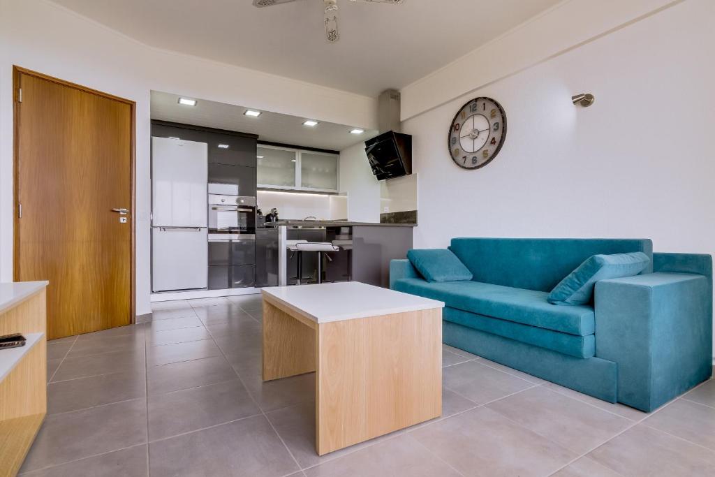 un soggiorno con divano blu e orologio sul muro di Hope House - 1 Bedroom - Vilamoura a Vilamoura