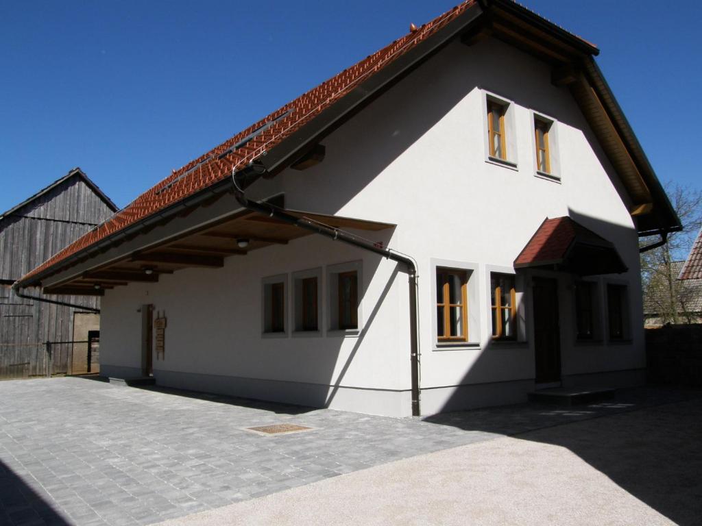 une maison blanche avec un toit rouge dans l'établissement Apartments Vrdjan, à Cerknica
