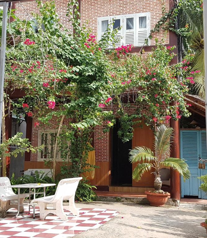 a building with a table and chairs and flowers at Tien Yoga House in Cái Bè