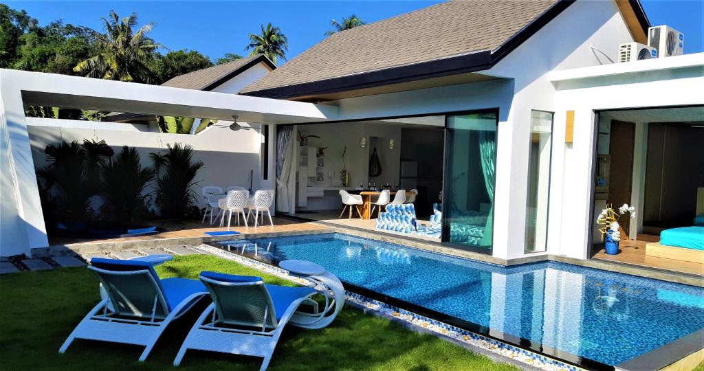 a swimming pool with chairs and a house at Villa KHAO MANEE in Ban Sakhu