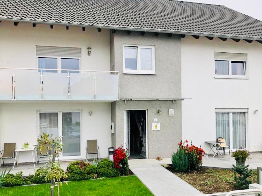 a white house with a balcony and a yard at Apartment in Hügelsheim