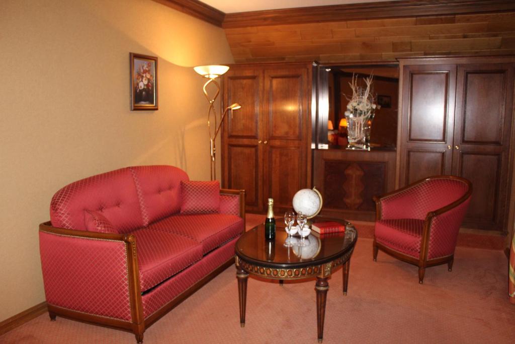 a living room with two red chairs and a table at Hotel Le Mandelberg in Mittelwihr