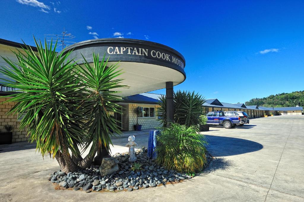 a parking lot with a caruana covenant sign and palm trees at Captain Cook Motor Lodge in Gisborne