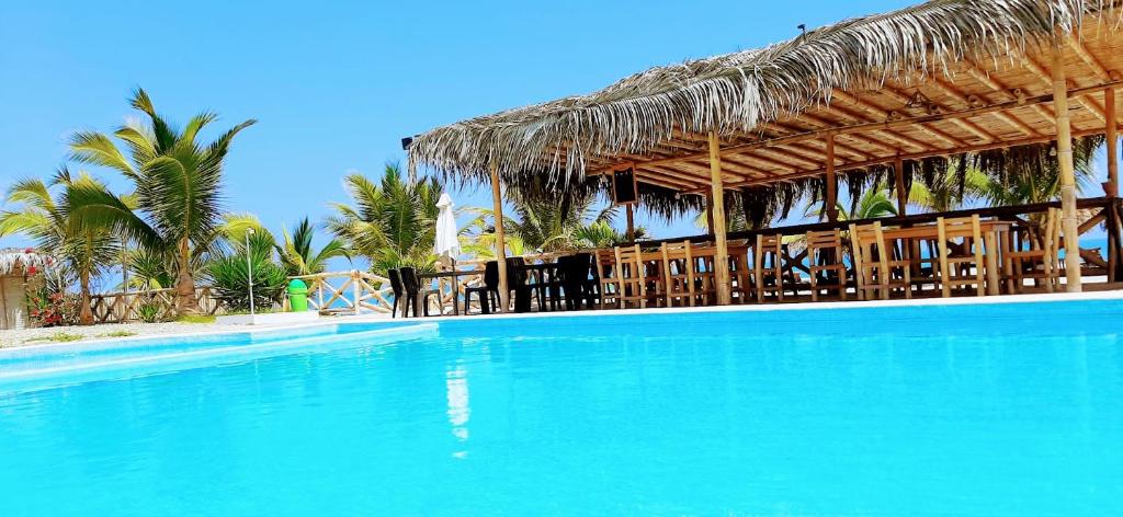 uma grande piscina com um resort com telhado de palha em Palo Santo Beach club em Bocapán