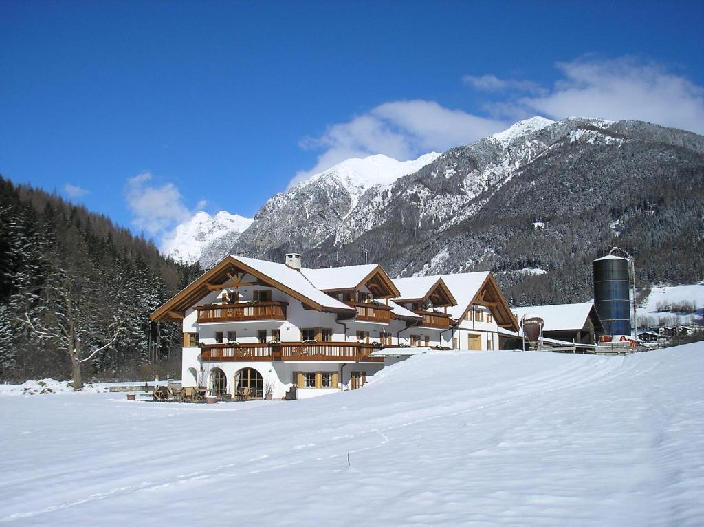 a lodge in the snow with snow covered mountains at Appartement Wolfenhof in Colle Isarco
