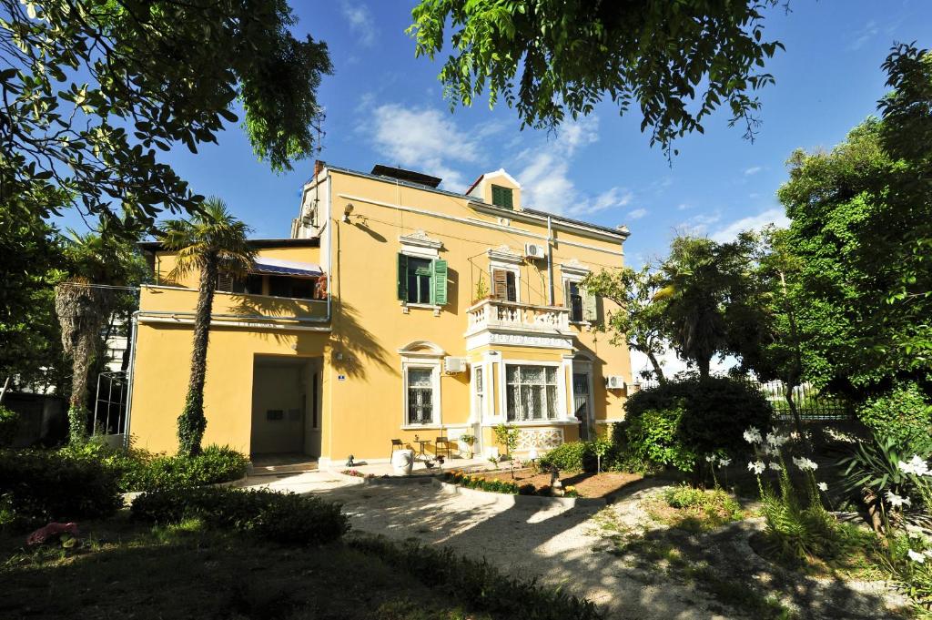 una casa amarilla con árboles delante de ella en Apartments Villa Ida, en Zadar