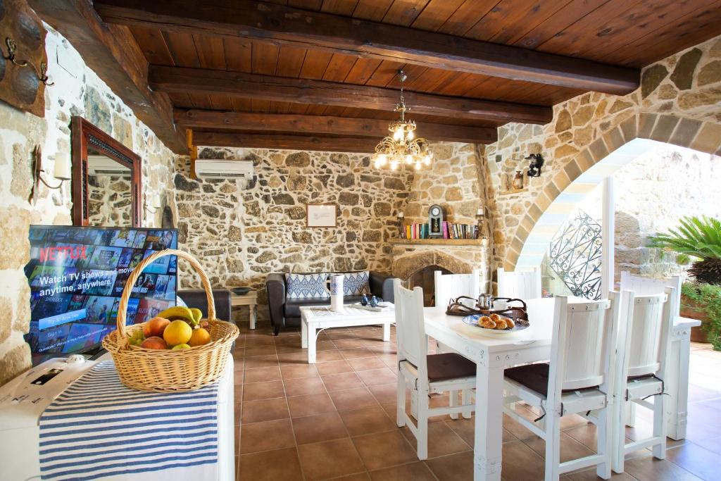 a dining room with a table and chairs and a stone wall at Villa Epimenidis in Sívas