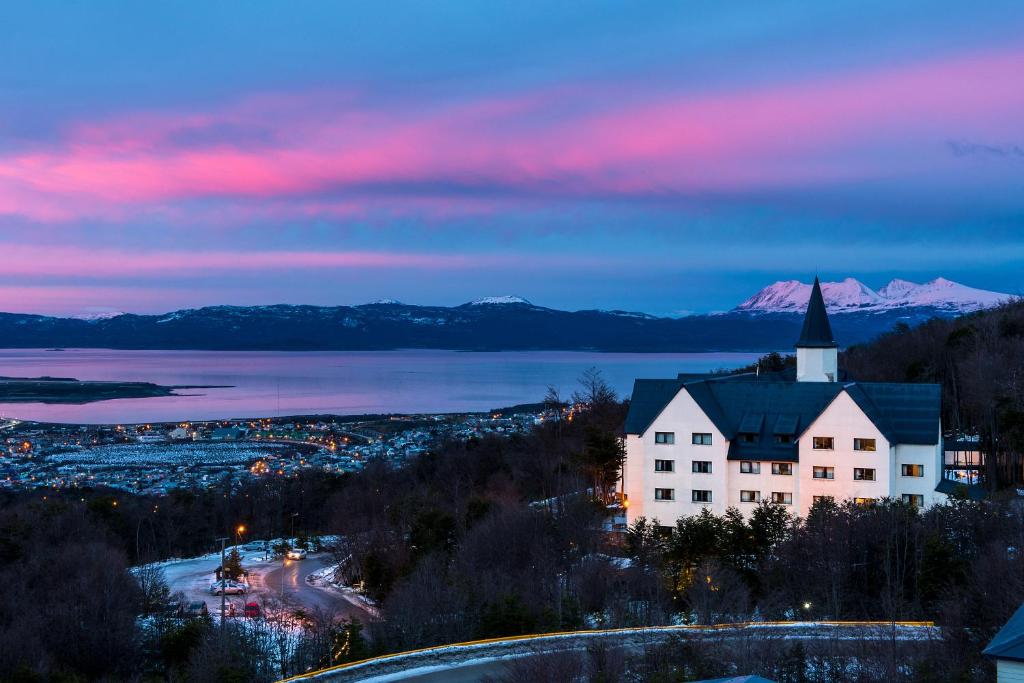 a building on a hill with a view of a lake and mountains at Las Hayas Ushuaia Resort in Ushuaia