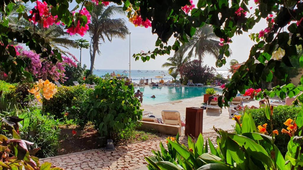 einen Swimmingpool mit Menschen im Wasser und Blumen in der Unterkunft Porto Antigo 2 Beach Club in Santa Maria