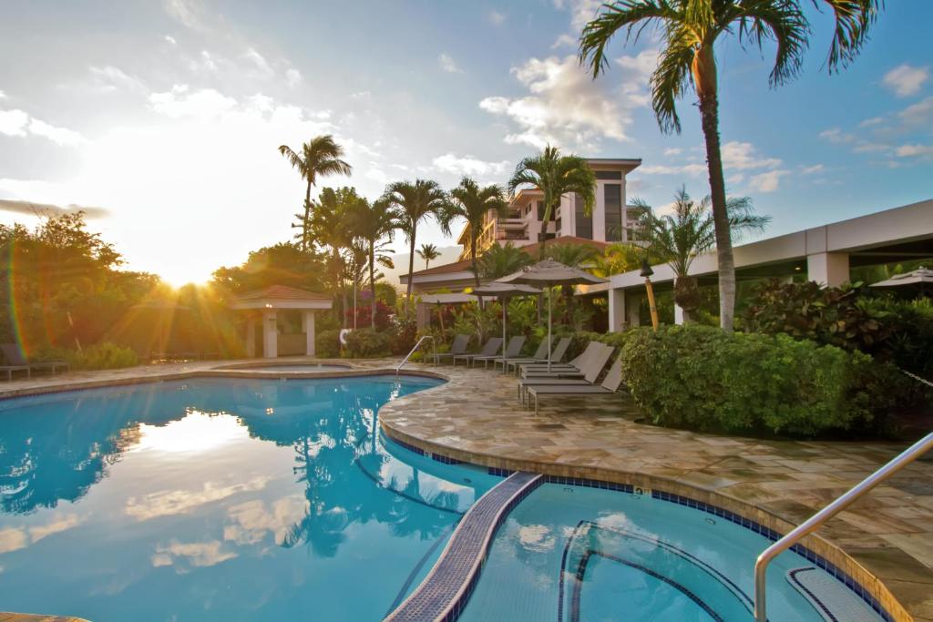 una piscina con palmeras y una casa en Maui Coast Hotel en Kihei