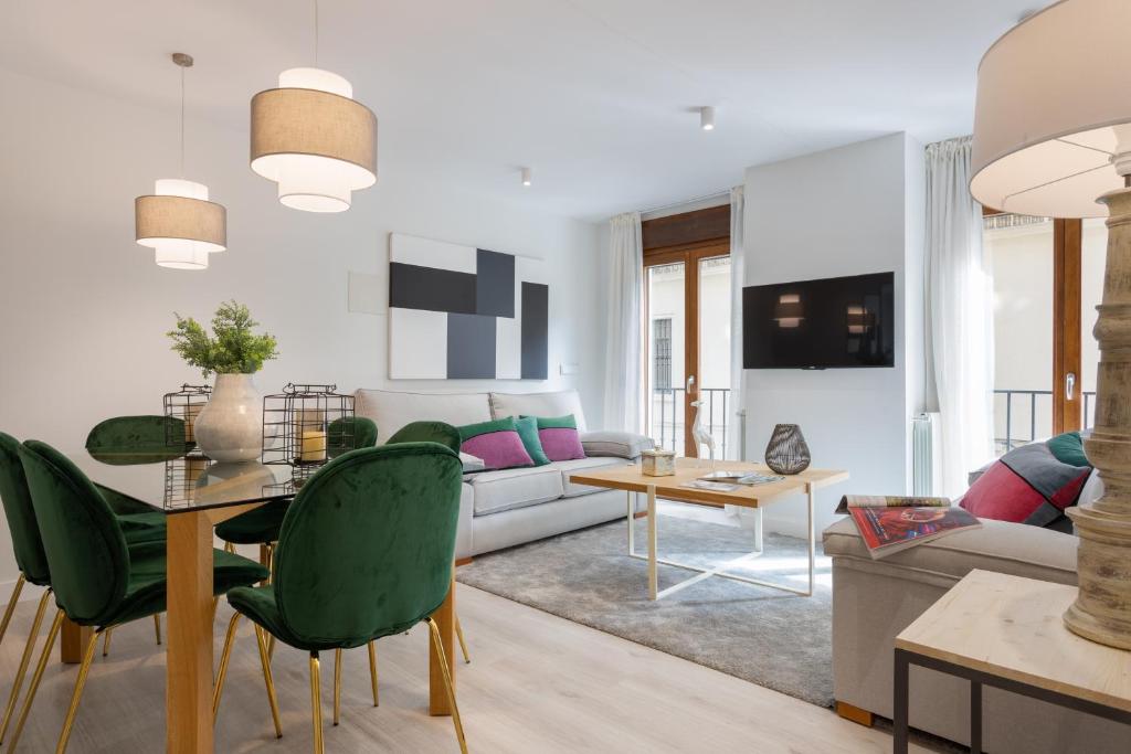 een woonkamer met een tafel en groene stoelen bij Genteel Home Cabildo in Sevilla