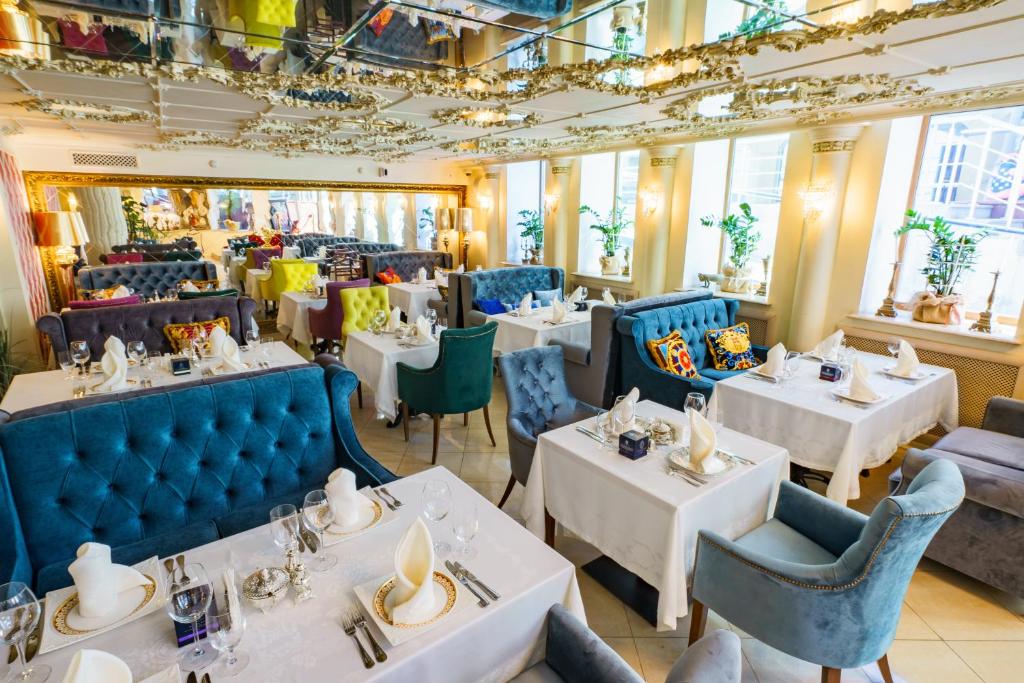 een restaurant met witte tafels en blauwe stoelen bij Golden Rooms Hotel in Moskou