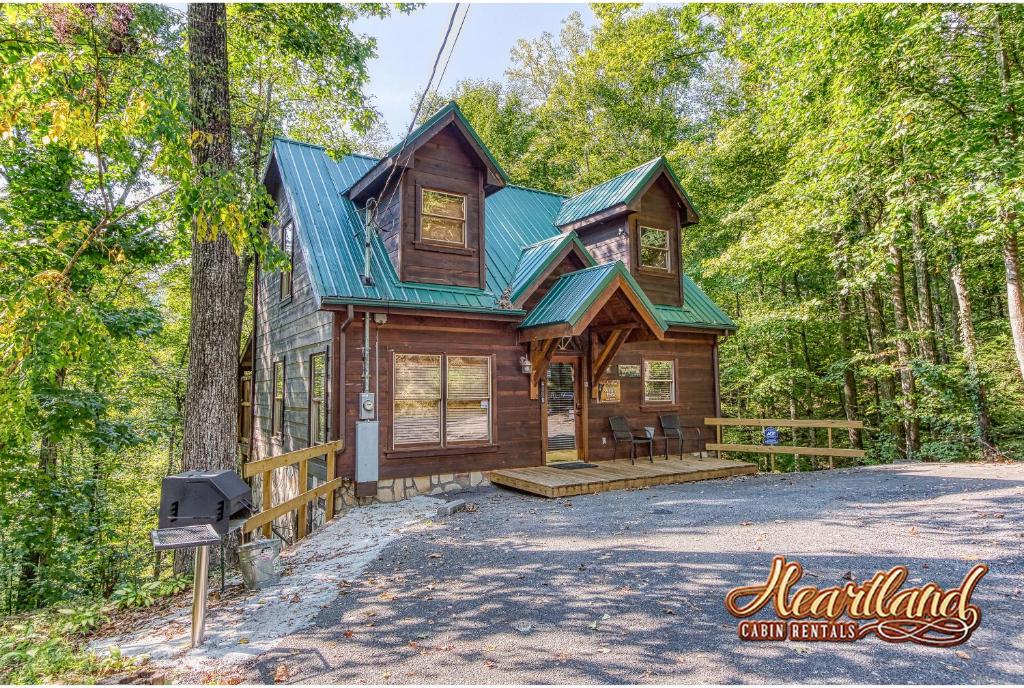 a cabin in the woods with a green roof at Naughty Pines in Pigeon Forge