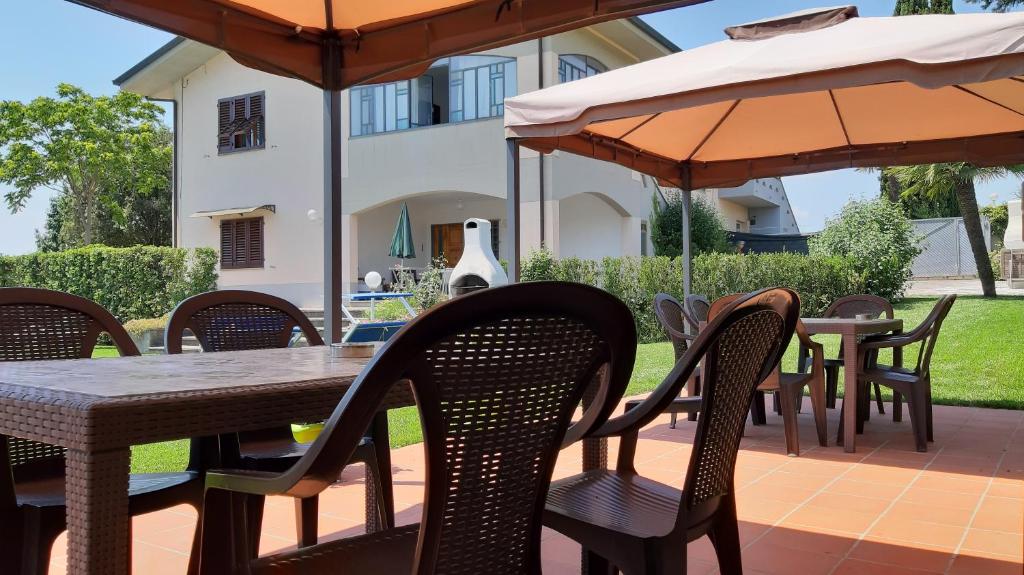 patio ze stołami, krzesłami i parasolami w obiekcie La Casa delle Rondini w mieście Lamporecchio