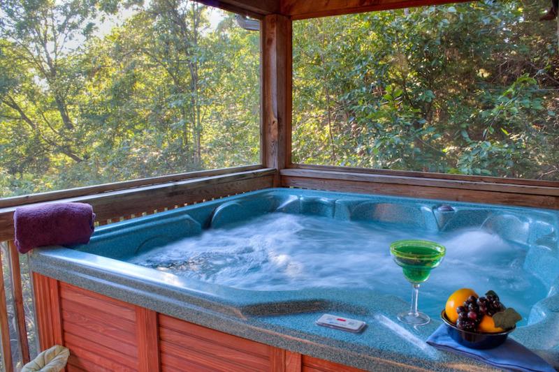 a jacuzzi tub with a glass of wine in it at Southern Comfort in Sevierville